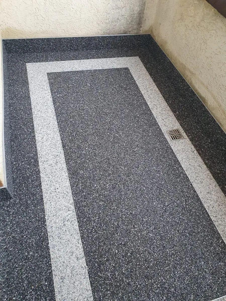 Ciemna nawierzchnia z ozdobnym obramowaniem przy wejściu